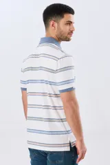 Remera polo de manga corta con diseño a rayas horizontales en tonos azules, celestes, verdes y beiges sobre base azul marino. Presenta cuello camisero con cierre frontal de botones y un pequeño logo bordado en el pecho.
