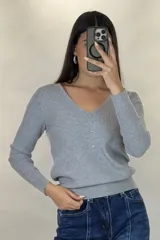 Buzo de hilo gris con textura acanalada, escote en V y cierre frontal con botones pequeños.