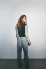Chaqueta de punto con diseño color block, cuello redondo y manga larga. Presenta cuerpo en color gris oscuro, mangas en gris claro y detalles de ribetes en color amarillo vibrante. Cierre frontal con botones oscuros.