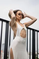 Vestido largo de punto blanco, con escote halter, abertura frontal tipo cutout bajo el busto, espalda descubierta y tajo lateral profundo en la falda.