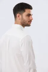 Camisa de lino de manga larga en color beige, con cuello camisero, cierre frontal de botones y un bolsillo ojal en el pecho.
