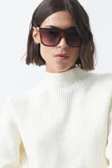 Polera de tejido de punto en color marrón oscuro, con cuello alto y diseño de silueta relajada.