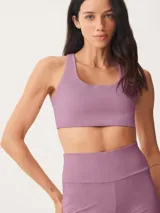 Top deportivo de escote redondo y espalda estilo nadadora, confeccionado en tejido elástico de color lila.