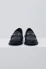 Mocasín negro de cuero con textura tipo cocodrilo, detalle de estribo metálico plateado en el empeine y costuras reforzadas en la puntera.