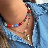 Collar dorado de doble cadena con dije de diente de tiburón.