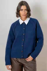 Saco de punto azul con cierre frontal de botones, cuello redondo y mangas largas con detalle de coderas.