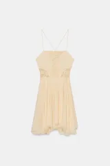 Vestido corto color crema/hueso, con escote recto y tirantes finos cruzados en la espalda. Presenta paneles de encaje en el centro del busto y a los lados de la cintura. La falda es fluida con godets y bajo asimétrico.