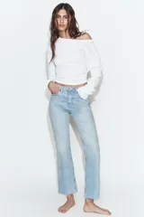 Jeans de tiro alto con diseño cropped flare, confeccionados en denim azul con acabado desgastado. Presentan cinco bolsillos, cierre frontal con cremallera y botón metálico, y bajo con terminación sin costuras.