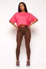 Remera corta de manga corta color celeste, con escote amplio en la espalda que se anuda en la parte inferior, dejando ver un top deportivo amarillo con tiras cruzadas.