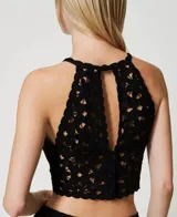 Top corto negro tejido a crochet con estampado floral, bordes festoneados y abertura en forma de lágrima.