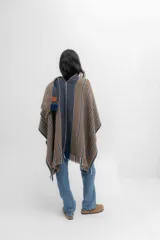 Ruana marrón con rayas horizontales azules y blancas, y flecos en los bordes.
