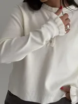 Sweater de punto color marrón chocolate, con cuello redondo y cierre frontal parcial con botones. Presenta mangas largas con puños acampanados y detalle de volados.