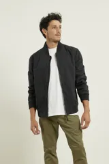 Campera tipo bomber color verde militar, confeccionada en 100% algodón. Cuenta con puños tejidos al tono, cuello y cintura elásticos, y cierre frontal metálico.