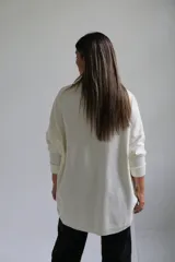 Polerón de punto color crudo, con cuello alto tipo polera, corte holgado y mangas largas con puños acanalados.
