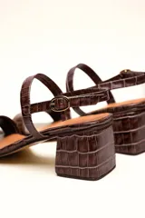 Sandalia de cuero vacuno color negro con textura de cocodrilo, taco cuadrado de 4 cm, punta cuadrada y dos tiras finas, una en el empeine y otra con hebilla en el tobillo.