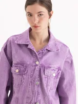 Campera oversize de denim de puro algodón, con lavado efecto nevado en tono lila. Cuenta con mangas largas, bolsillos frontales con solapa y cierre de botones metálicos.