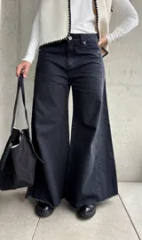 Jean de corte oxford y tiro medio, color negro lavado. Presenta diseño de pierna ancha con costuras verticales decorativas y ruedo deshilachado.