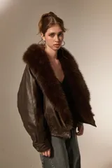 Campera de eco-cuero color marrón con cuello amplio de piel sintética al tono. Presenta un diseño de corte holgado, mangas largas y cierre frontal con botones.
