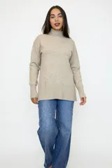Buzo de punto color camel con cuello alto, manga larga y diseño de corte relajado con terminaciones acanaladas en puños y ruedo.