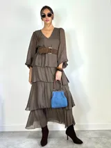 Vestido largo de seda italiana color chocolate, con escote en V, mangas largas abullonadas y diseño de falda con volados escalonados.