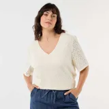 Camiseta de encaje color beige con diseño calado, escote en V y mangas cortas abullonadas.