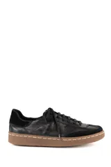 Championes de estilo urbano confeccionados en cuero negro con textura, con detalles en gamuza y suela de goma color marrón con costura a la vista.