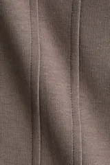 Remera de manga corta color marrón topo en punto interlock pesado, con cuello redondo y diseño entallado en la cintura con pinzas moldeadoras en el frente que generan una silueta peplum.
