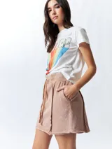 Minifalda color beige con elástico en la cintura, cordones ajustables y costuras marcadas en los laterales.