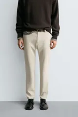 Pantalón de corte slim fit confeccionado en tejido elástico, con cintura elástica, cierre frontal con cremallera y botón, bolsillos laterales y bolsillos traseros de vivo.