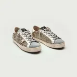 Zapatillas bajas con base blanca, cuerpo con glitter plateado y detalles en gamuza celeste y cuero blanco. Presenta un rayo dorado en el lateral externo.