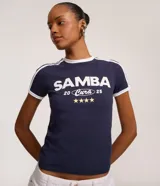 Remera ajustada de algodón color azul marino con cuello redondo y ribetes blancos en el cuello y mangas. Estampado frontal en blanco con el texto "SAMBA 20 Cura 25" y cuatro estrellas doradas debajo.