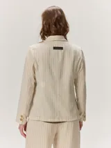 Blazer de lino color negro con pespuntes en contraste de hilo tostado, cuello solapa amplia, cierre frontal con un botón de madera y bolsillos aplicados.
