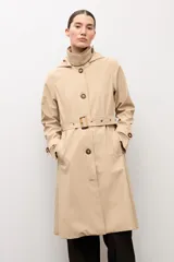 Trench clásico color beige, con cuello alto, capucha desmontable, cierre frontal de botones marrones, bolsillos ribeteados y cinturón ajustable con hebilla.