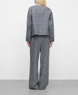 Pantalón de lino gris con estampa de cuadros, tiro medio y pierna ancha. Presenta pliegues frontales, cierre con botón y elástico en la parte posterior de la cintura.