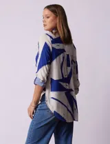 Camisa de manga larga con estampado abstracto en tonos verde y blanco. Cuello con solapa y abertura central con botones. Largo de manga regulable con presilla y botón. Terminación de ruedo anudada opcional.