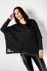 Poncho tejido en Lurex negro con hilos plateados brillantes, escote en V y mangas largas. Presenta un calce suelto y relajado.