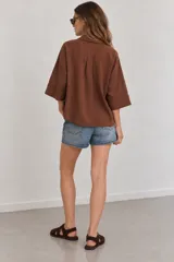 Camisa de lino blanca oversize, con cuello solapa, mangas anchas y cierre frontal con botones.