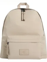 Mochila Calvin Klein Metro Nylon color beige, confeccionada en nailon reprocesado. Cuenta con un compartimento principal con cierre de cremallera, un bolsillo exterior frontal con cierre, asa superior y parche con monograma CK grabado.