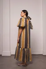 Vestido largo y amplio con cuello alto y mangas cortas abullonadas. Diseño a rayas verticales en tonos dorado y gris. Incluye viso liso al tono.