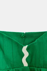 Top corto de lino color verde, con escote en pico, tirantes finos ajustables y detalle de ondas decorativas en color crema. Presenta un diseño con vuelo en la parte inferior y cierre en la espalda.
