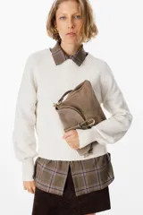 Cartera de hombro confeccionada en cuero gamuzado color chocolate, con solapa frontal y cierre mediante una tira de cuero con herraje metálico en forma de herradura.