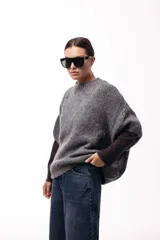 Sweater de tejido de punto grueso con silueta amplia y mangas 3/4. Presenta un diseño de calce relajado con cuello redondo y textura voluminosa.