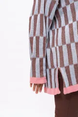 Saco de punto con diseño de bloques geométricos en tonos celeste y marrón, con cuello redondo, cierre frontal de botones y terminaciones en color rosado.