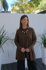 Sweater de tejido de punto en color chocolate, con corte holgado, cuello redondo y mangas largas. Presenta un diseño con bolsillos frontales integrados y terminaciones acanaladas en puños y ruedo.