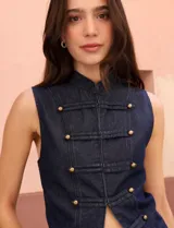 Chaleco de denim azul oscuro con cuello mao y cierre frontal mediante alamares con botones metálicos dorados.