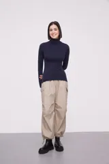 Polera de tejido de punto fino en color azul marino, con cuello alto y mangas largas. Presenta un ajuste al cuerpo y terminaciones acanaladas en cuello, puños y ruedo.