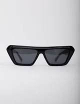 Lentes de sol negros con marco rectangular grueso y patillas anchas.