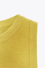 Top de punto color amarillo mostaza, con cuello redondo y manga sisa. Acabados en rib a tono.