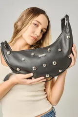 Cartera bandolera de cuero negro con diseño de media luna, decorada con tachas metálicas plateadas. Cuenta con correa regulable, cierre principal y bolsillo interior con forro.