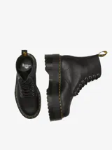 Botas Dr. Martens modelo 1460 Pascal Max de cuero negro, con plataforma gruesa acanalada, cordones negros, ojales metálicos plateados y costuras amarillas distintivas. Incluye tirador trasero con logo en amarillo y negro.